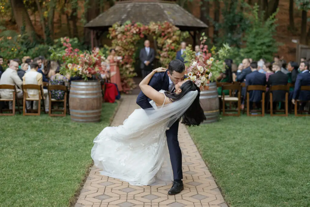 Bride and groom kissing at the end of the ceremony aisle.
